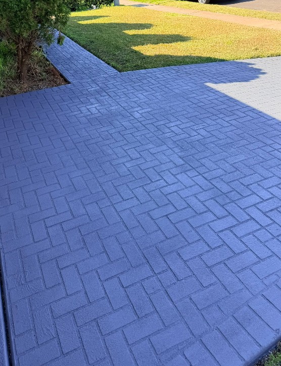 Close up of a sealed concrete driveway in a herringbone pattern