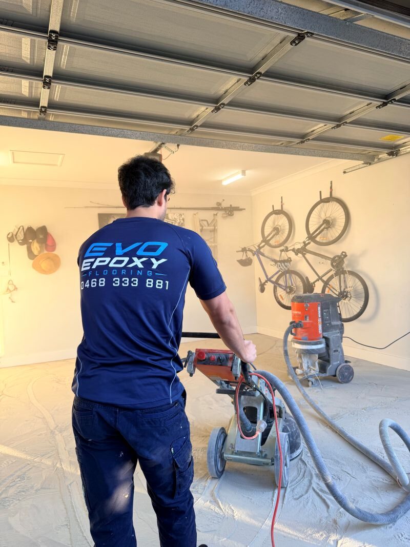 Evo Epoxy grinding a garage slab with dust extraction before coating