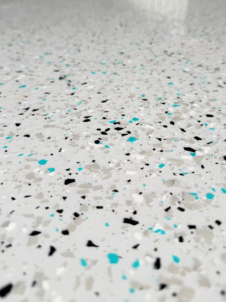 Close up of teal, black and white vinyl flake in an epoxy floor
